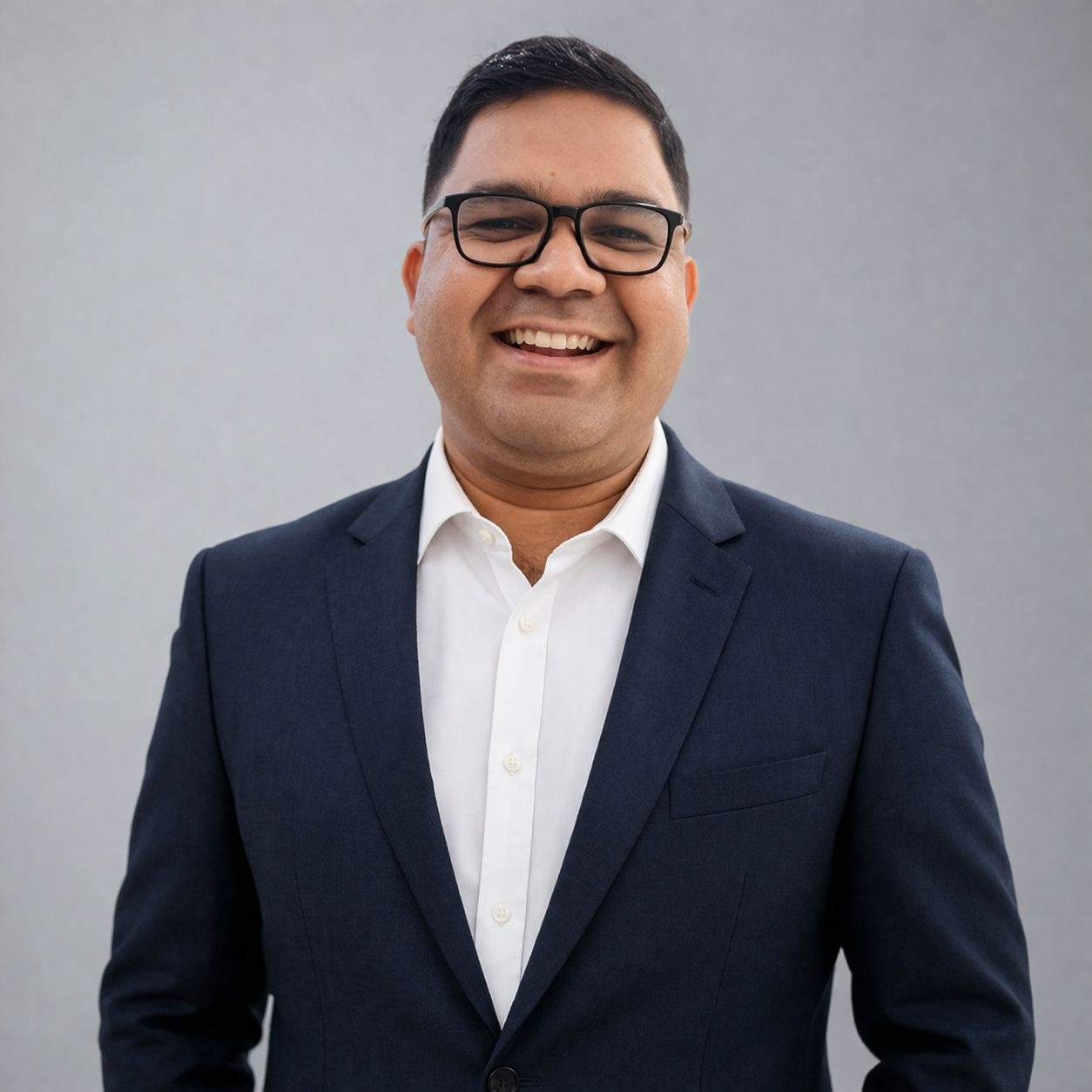 Dr. Sibani Sankar Tripathy, physiotherapist and chiropractor, in a navy suit against a neutral grey backdrop