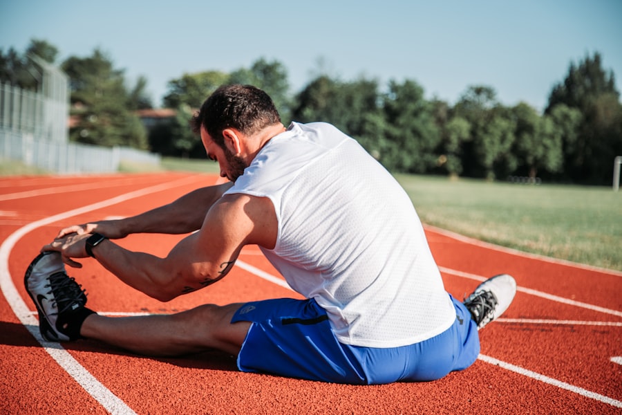 A runner stretching at the side of an athletics track